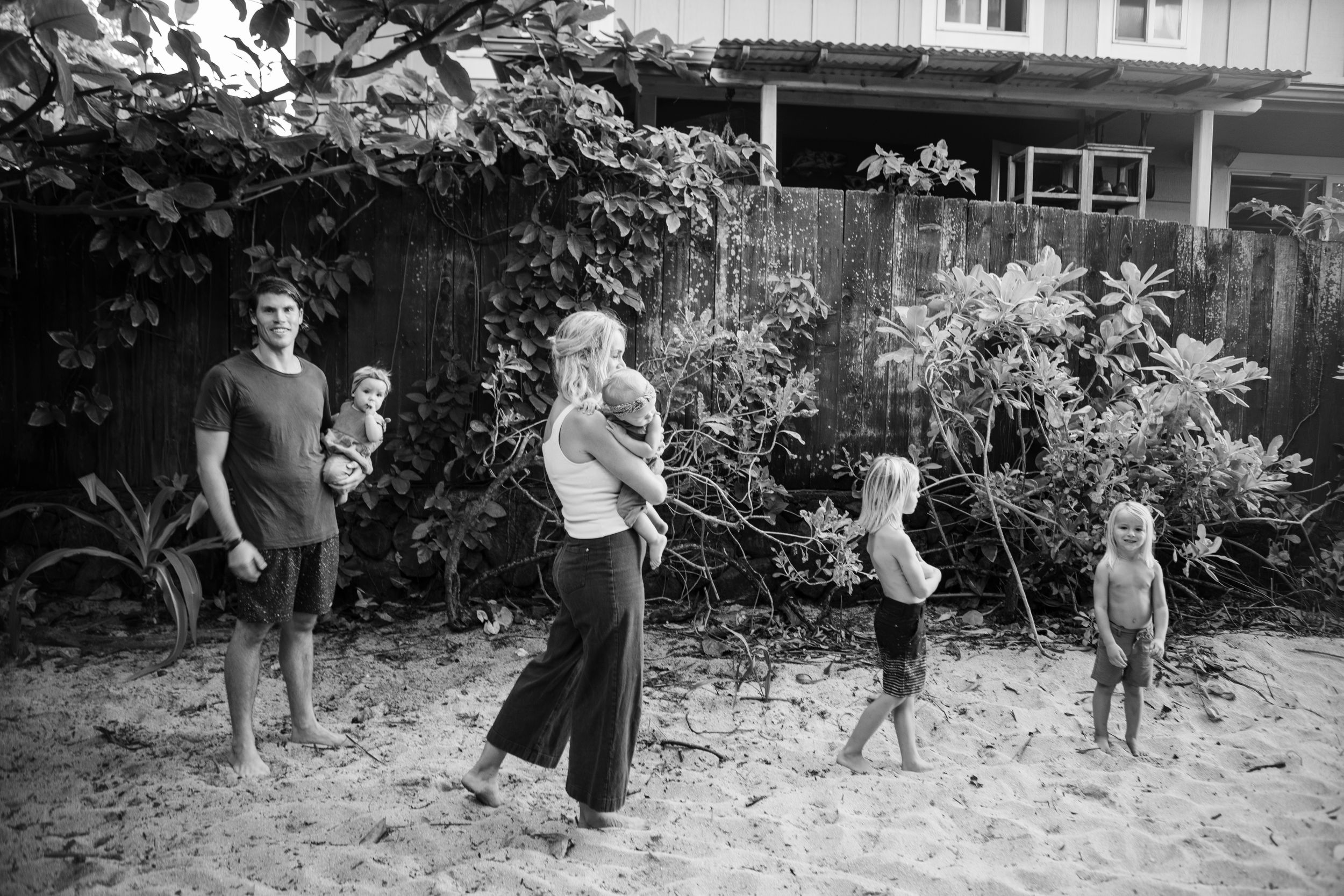 A series of black and white snapshots showing people doing yard work and clearing debris from a garden area together.