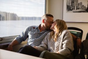 Couple sharing an intimate moment while relaxing on couch by window in casual home setting.