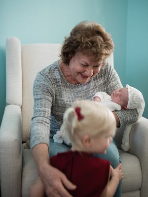 A heartwarming family moment in a white armchair shows loving interactions with a newborn baby in a cozy room.