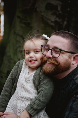 A heartwarming series of candid moments showing affection between a bearded person in glasses and a small child outdoors.