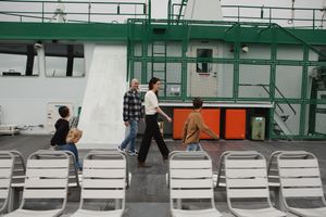People sitting on white benches in a subway or train station with green walls and tiled floors.