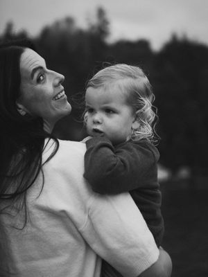 A black and white photo series shows a parent and child in an intimate moment of connection and play outdoors.