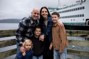 A family enjoying a scenic coastal view together while posing outdoors near a ferry boat.