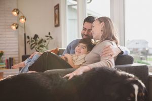 A couple embraces on a couch in a cozy living room with natural lighting and brick walls.