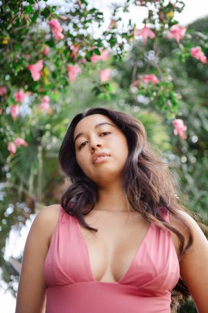 Series of outdoor photos with pink flowers in background and person wearing rose-colored top.