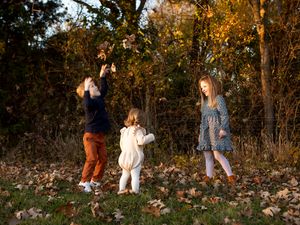 Series of five cropped photos showing people walking through autumn woods with fallen leaves scattered on the ground.