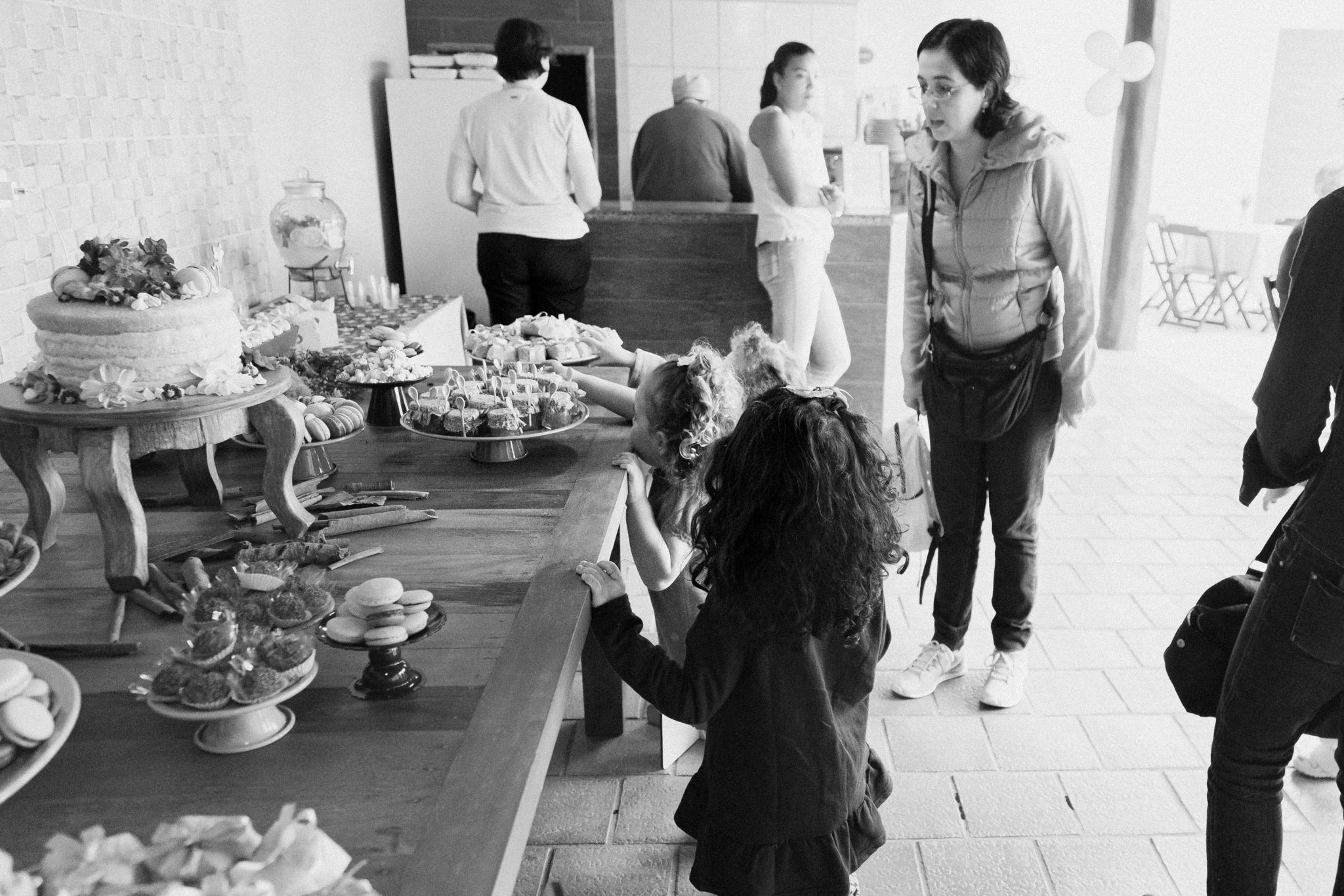 A row of guests gathering around a buffet table at a social event in black and white.
