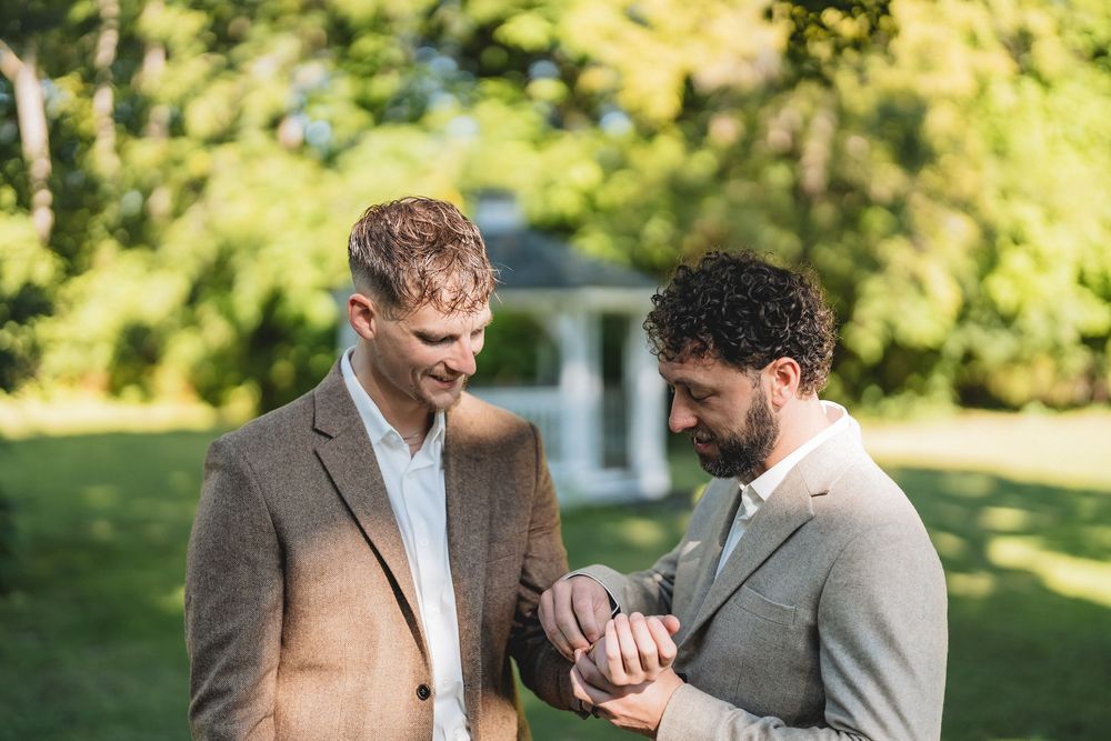 Two people in wedding attire sharing an intimate moment in a sunny garden setting.