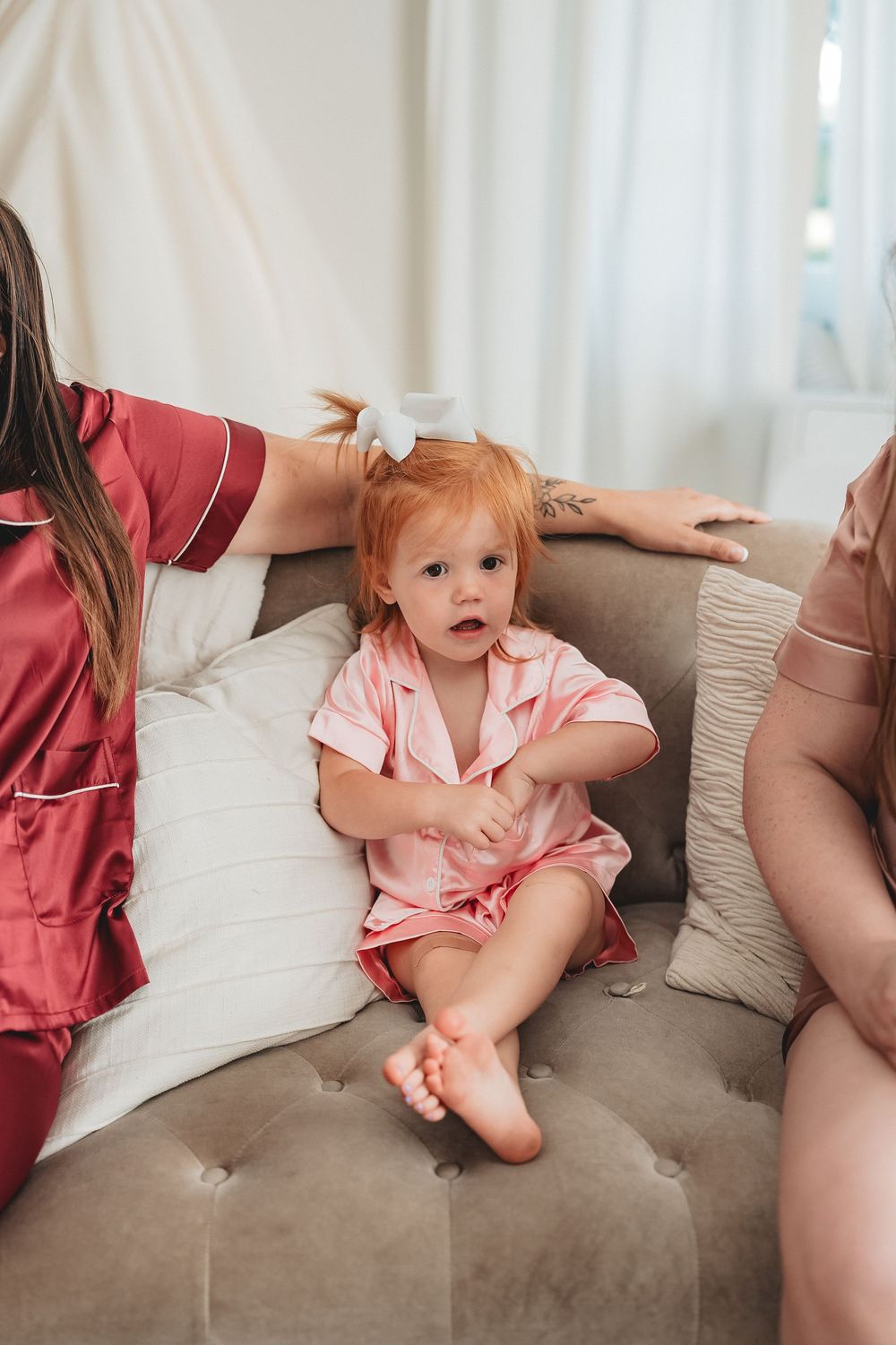 A baby in pink pajamas sits on a gray couch with emotions changing across four sequential photos.