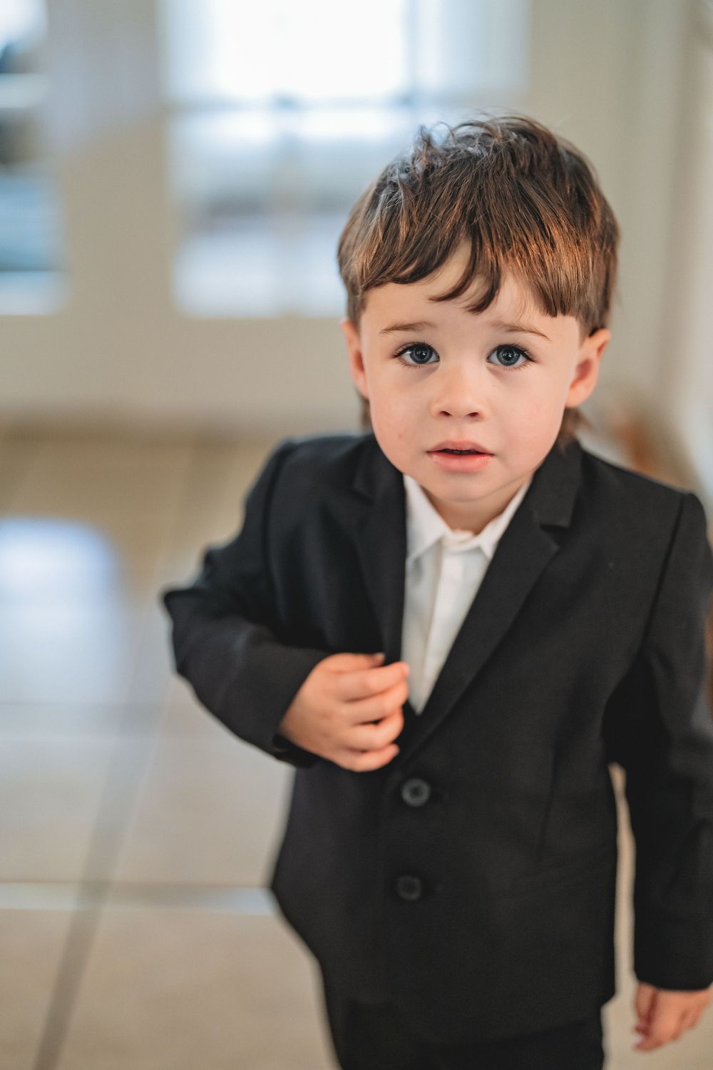 A series of photos showing a small child in a black suit and gray tie making various playful expressions.
