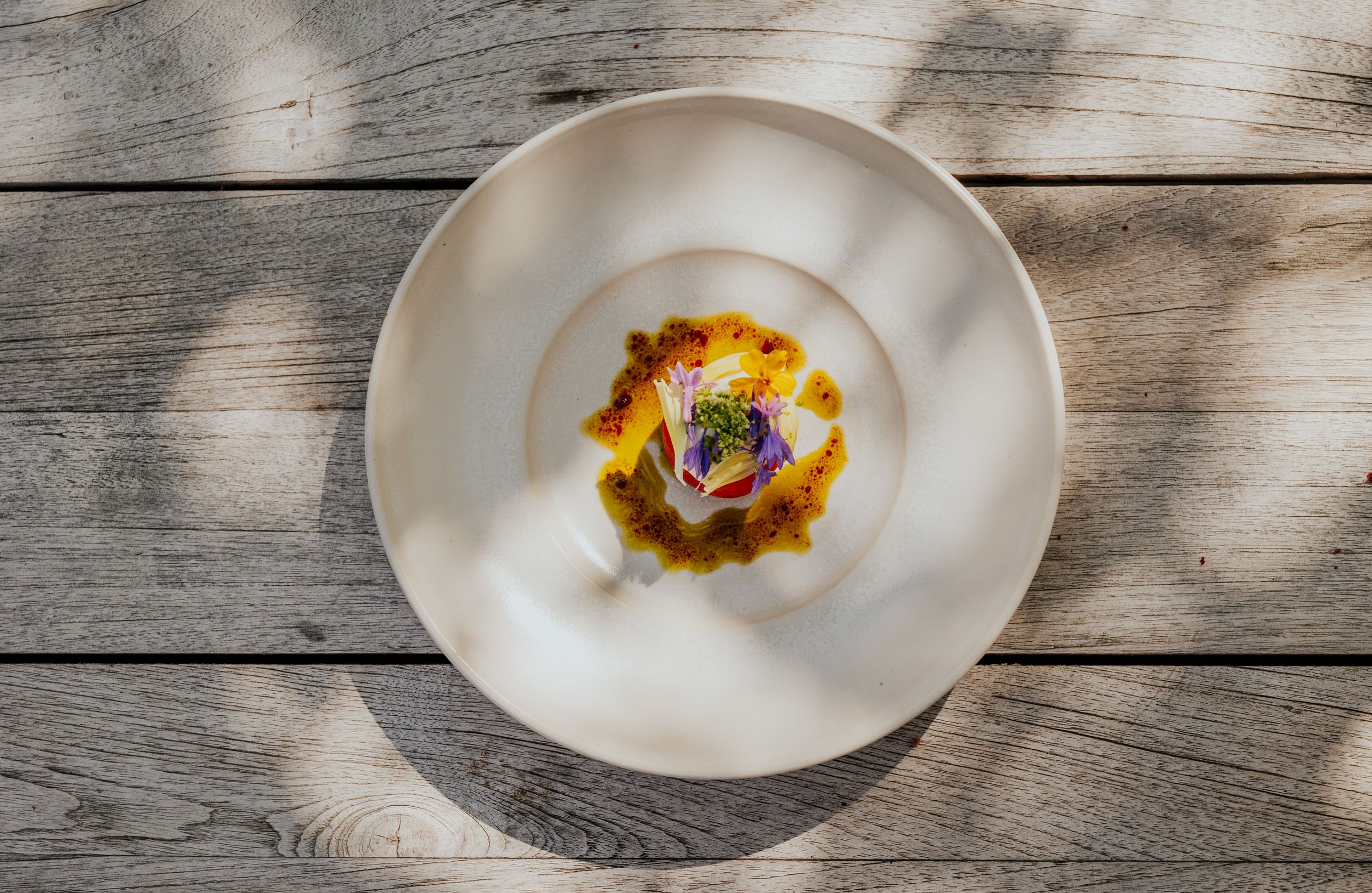Elegant white plate with a delicate culinary creation in natural lighting on wooden table.