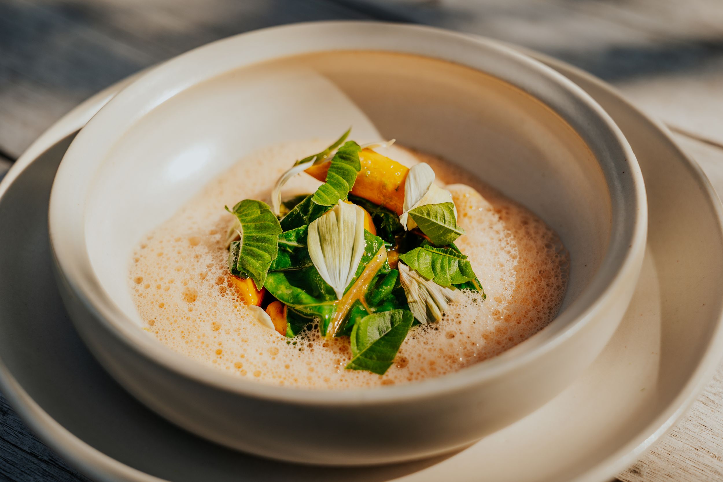 Creamy soup garnished with fresh herbs and microgreens on elegant white dinnerware.