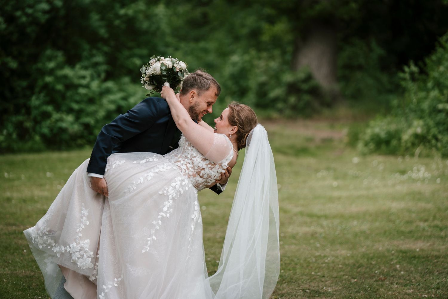 Close-up of hands exchanging wedding rings during an outdoor ceremony.