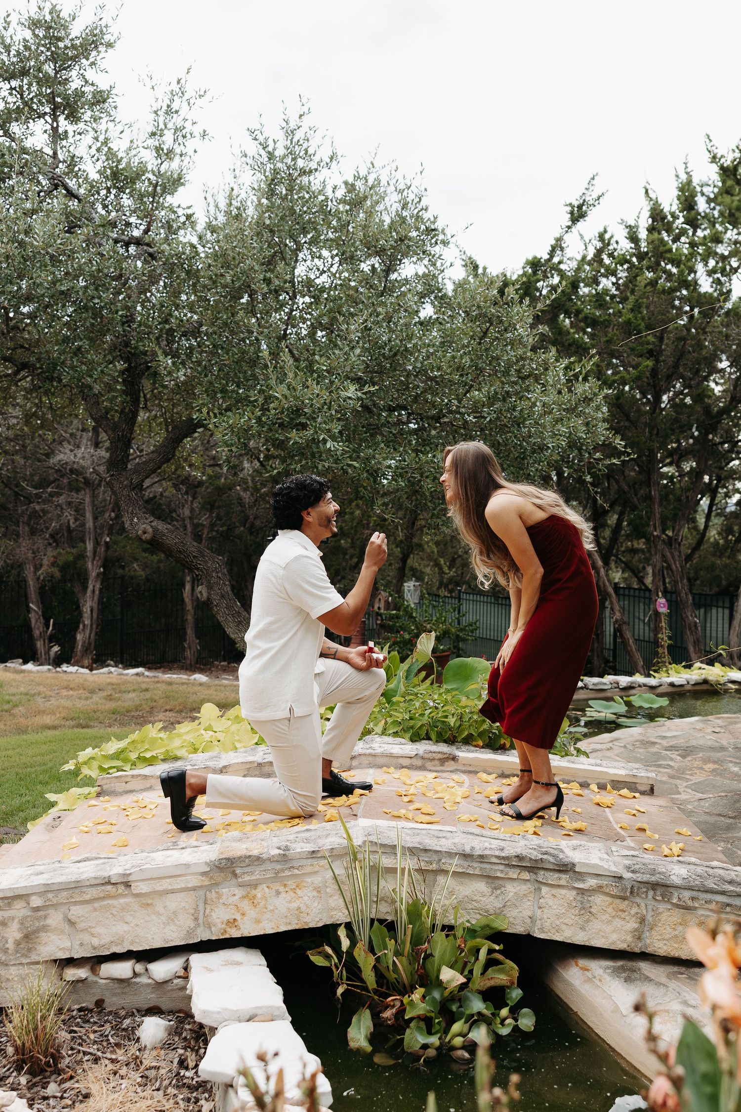 A proposal scene in a field of tall grass with trees in the background.