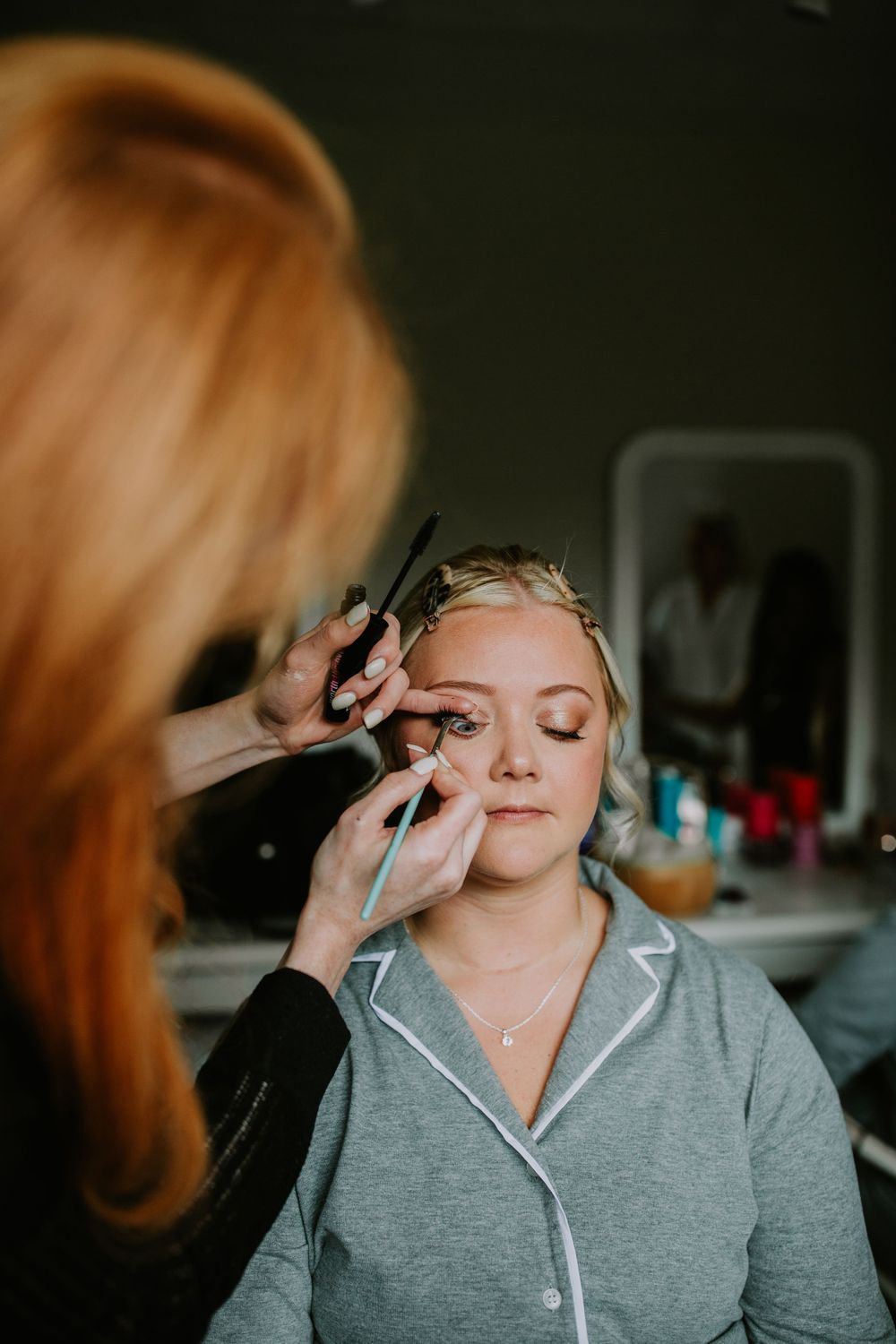 Wedding preparation scene showing makeup application in a dimly lit room.