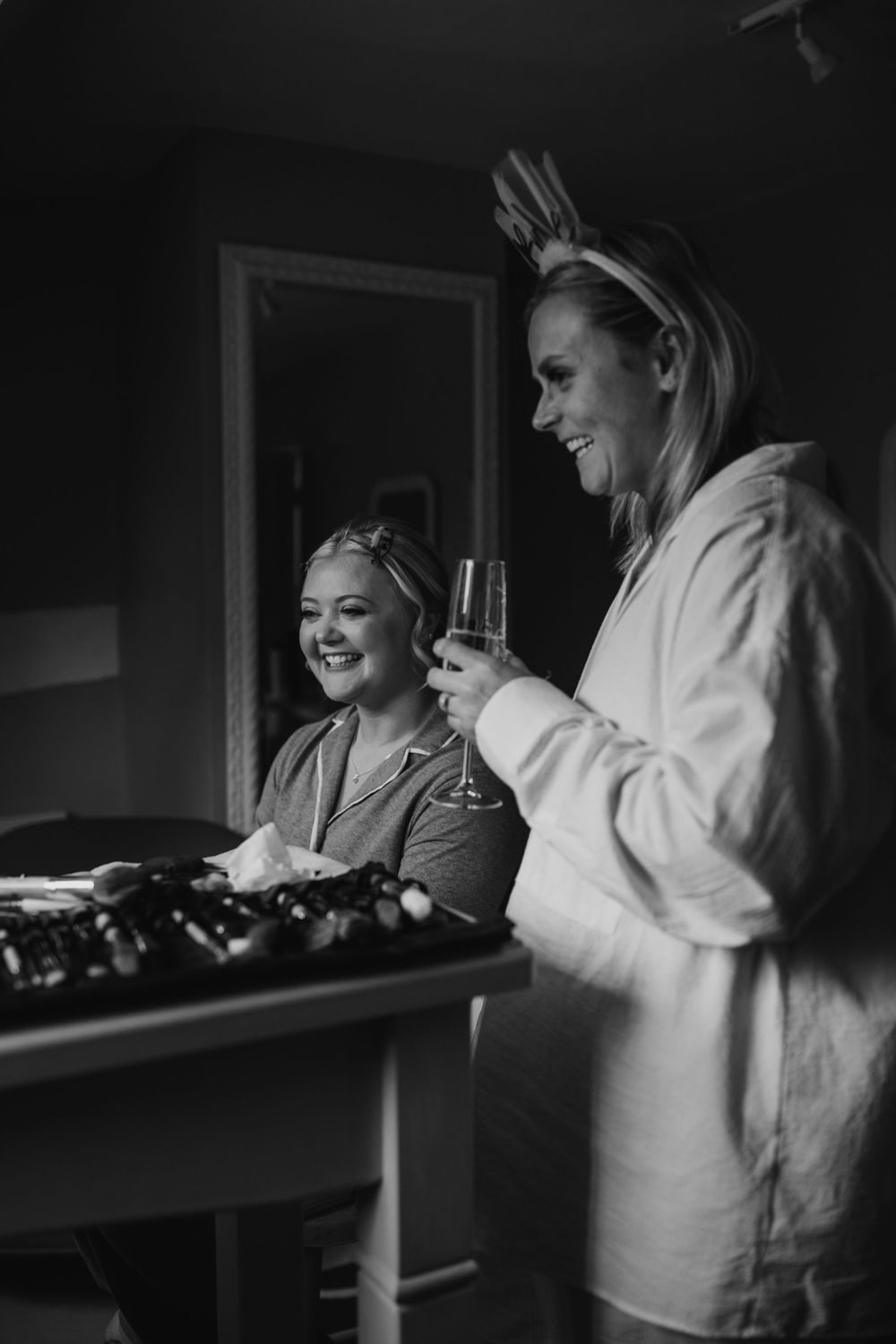 Black and white image of wedding morning preparations with champagne and robes.