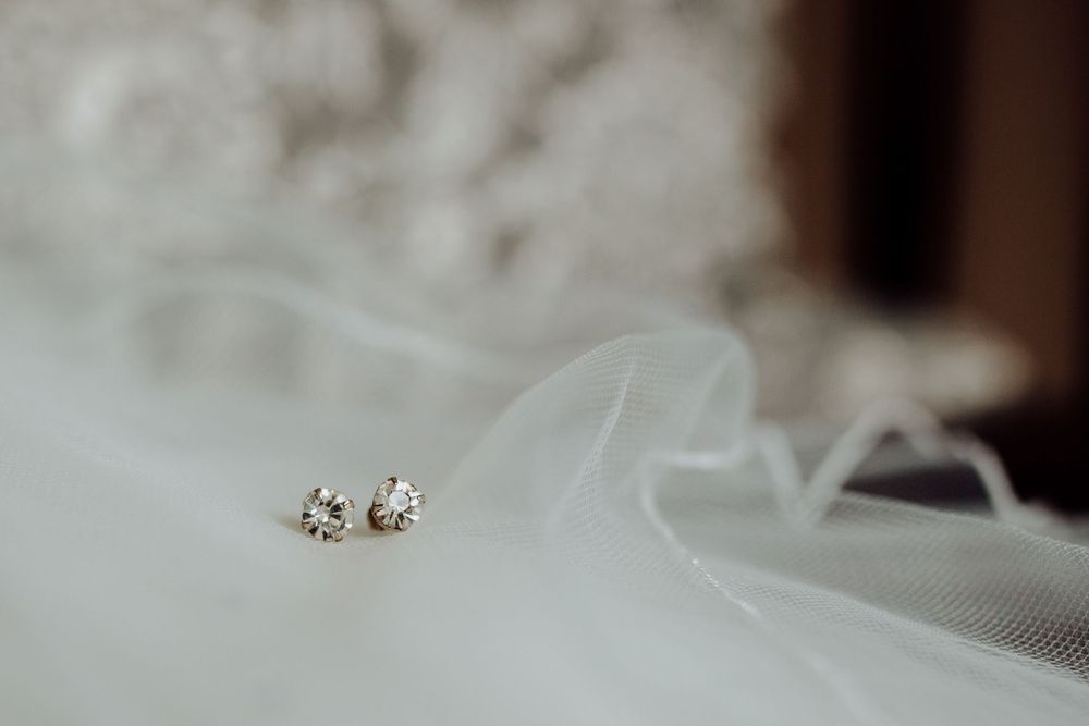 Delicate diamond stud earrings nestled in soft white tulle veil fabric.