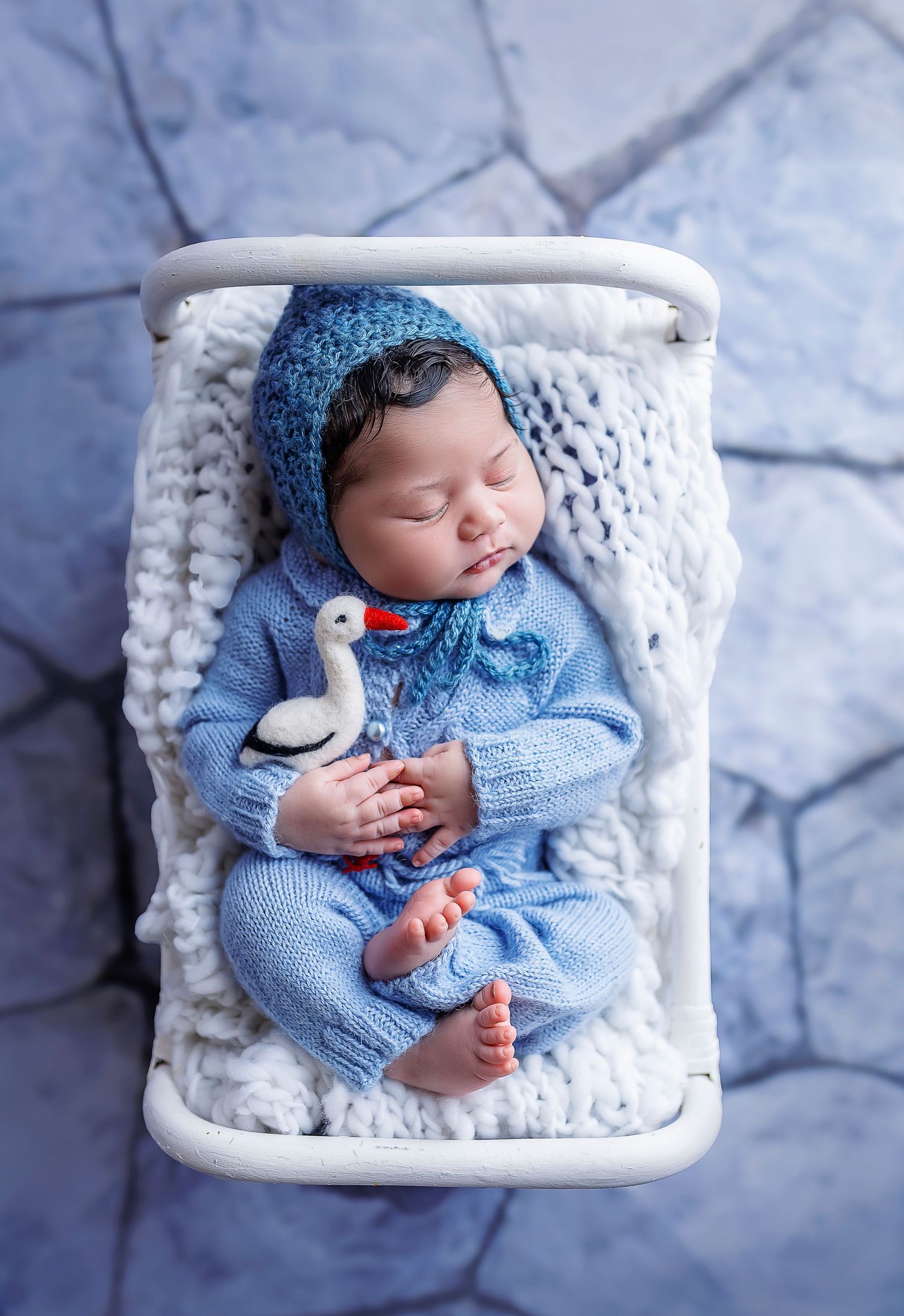 bebe vestido de azul durmiendo en camita de rattan, aguanta un juguete con forma de pajaro Fotografa de bebes en Ponce Puerto Rico
