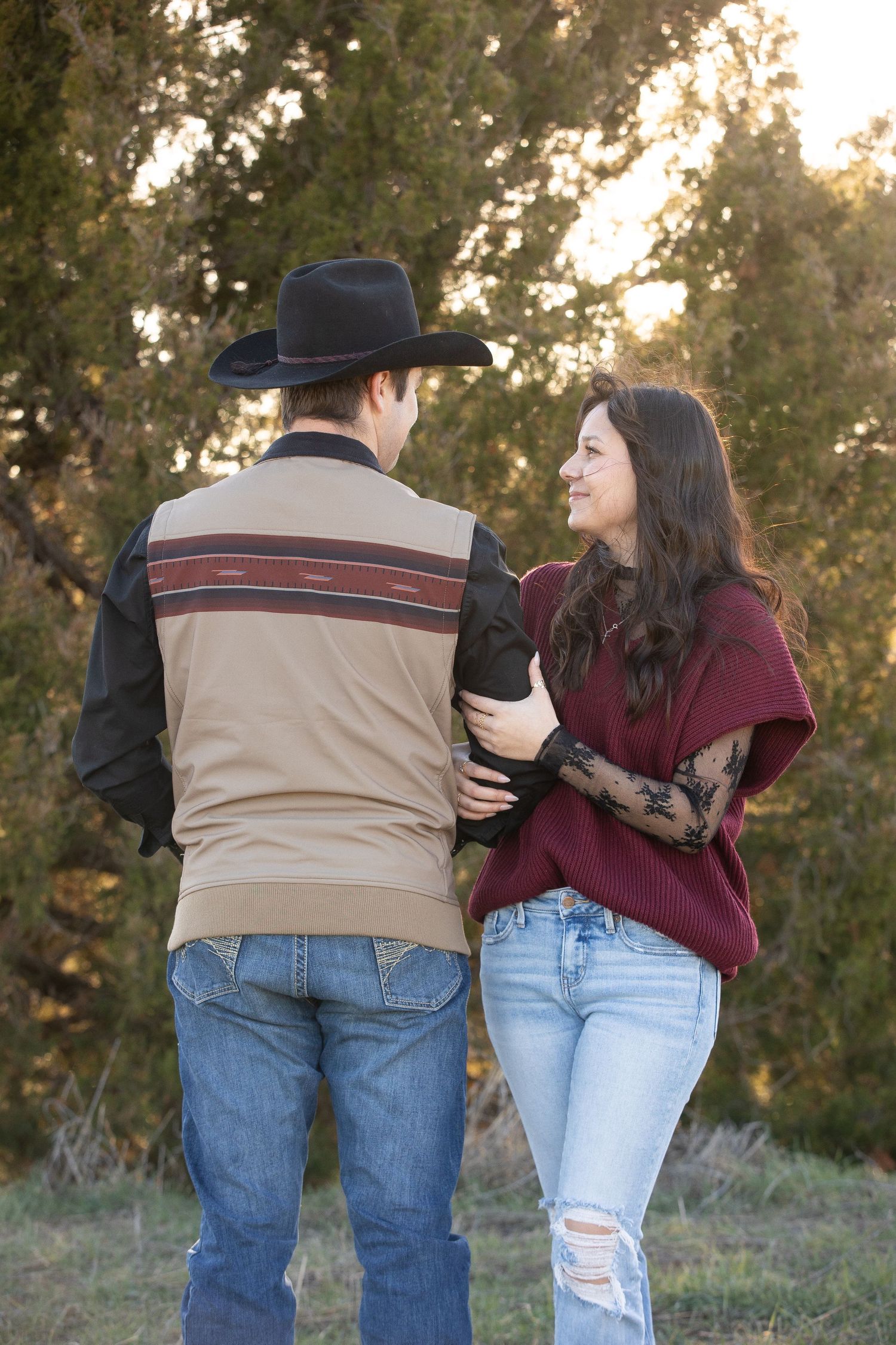 A couple in casual attire sharing a playful moment outdoors during golden hour.