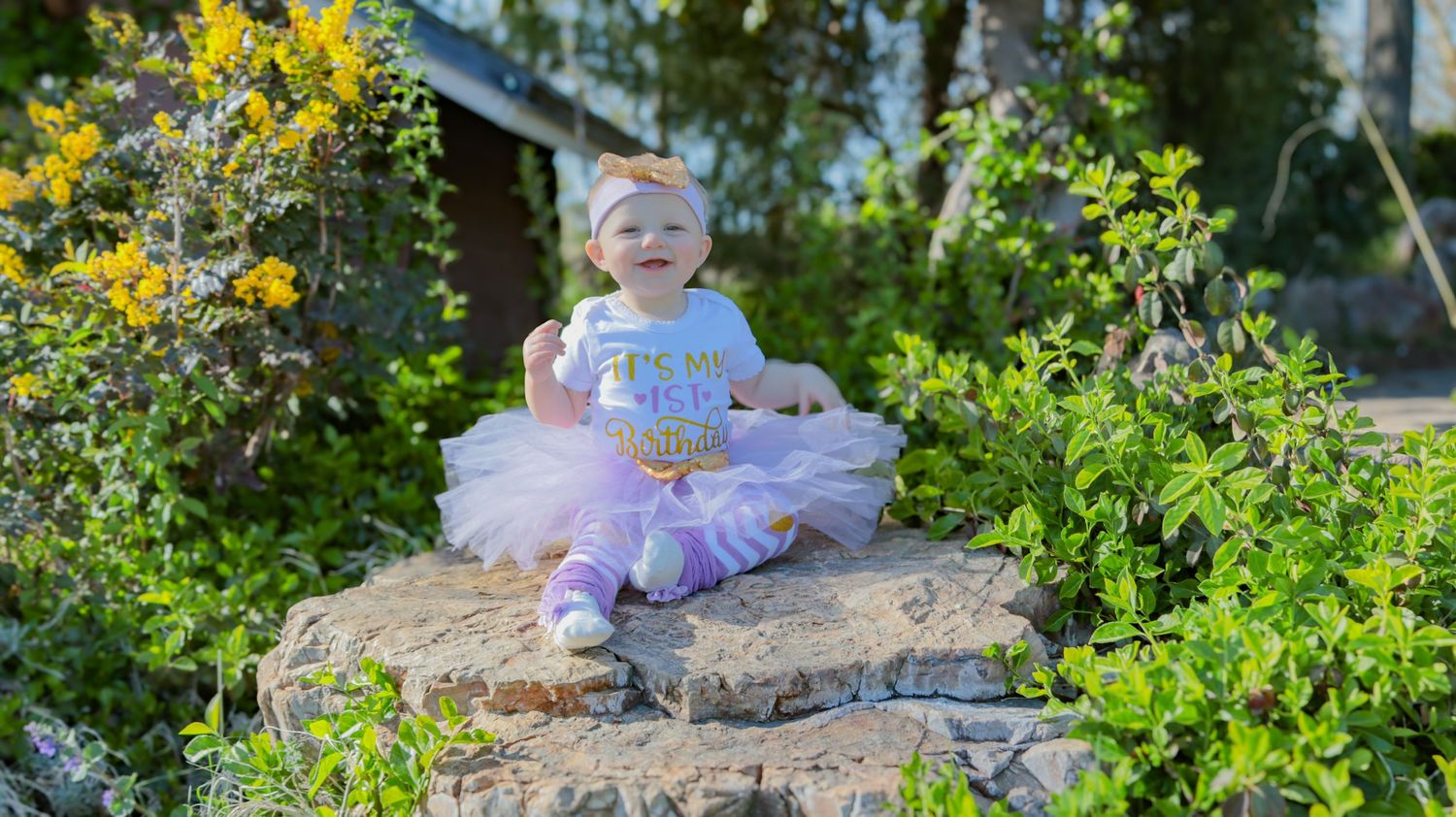Baby girl sitting on a rock at the International Peace Gardens during a first birthday photo session in Salt Lake County, Utah