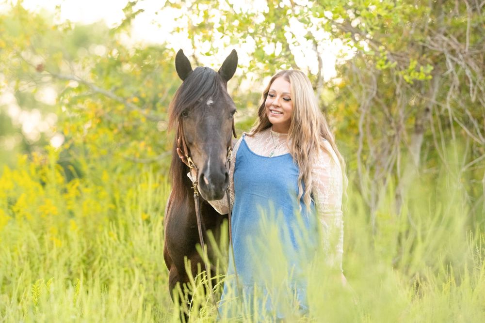 Horse and handler portrait session in field of yellow wildflowers during golden hour.