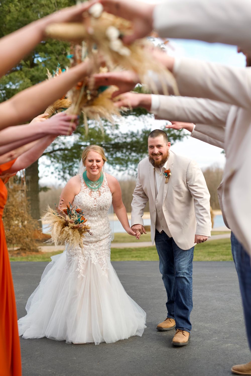 Wedding guests form a tunnel with raised arms as newlyweds dance underneath on their special day.