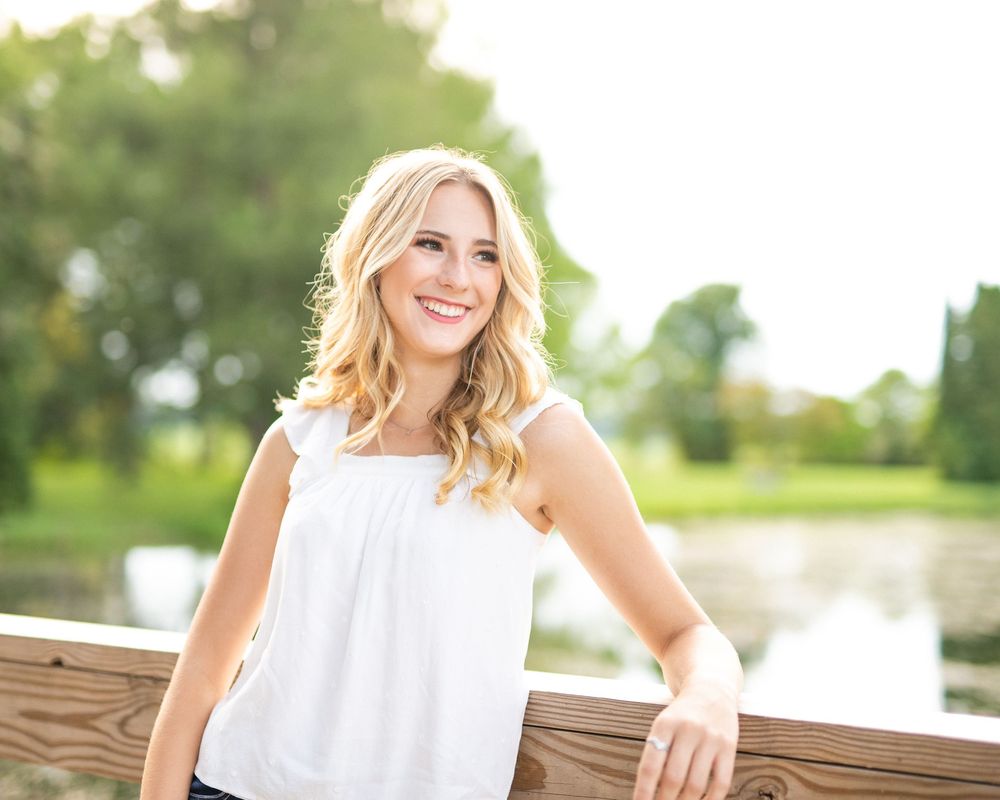 Portrait session on a wooden bench with soft natural lighting in an outdoor setting.