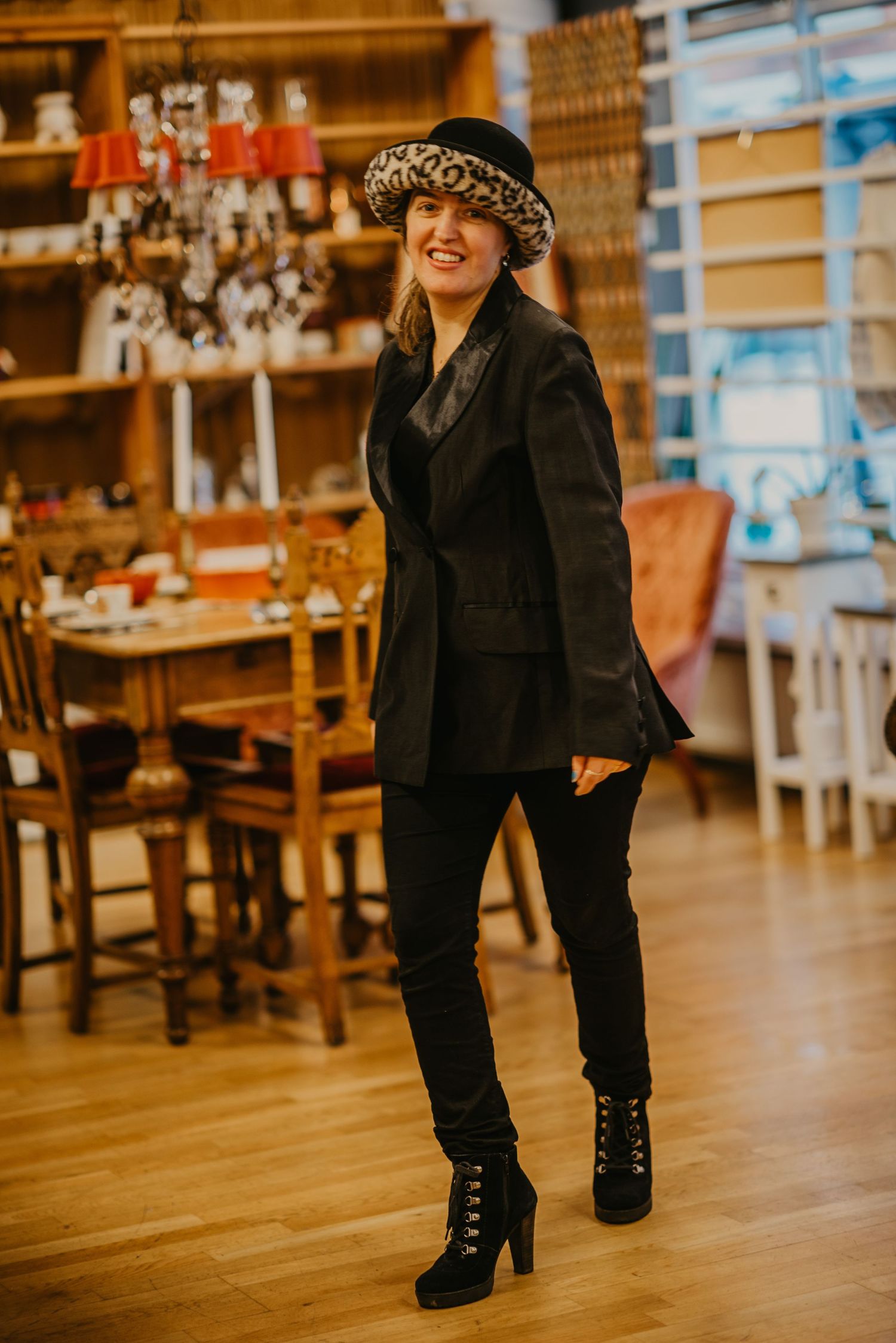 Four sequential photos show a person in all black attire and boots posing against a warm-toned restaurant interior.