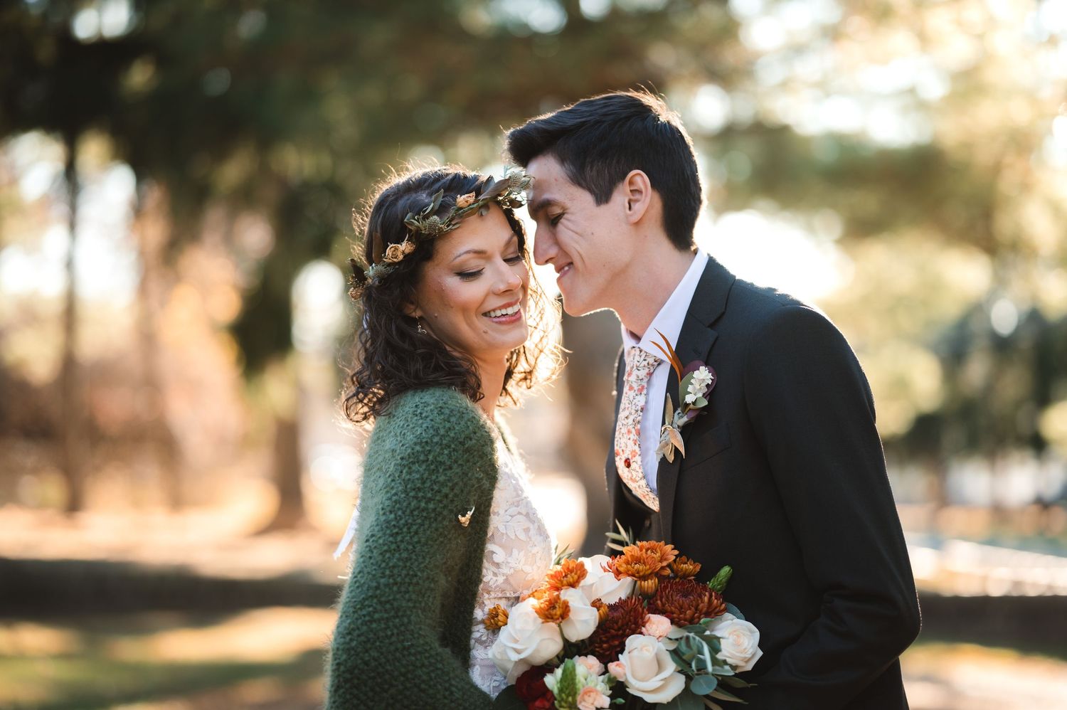 A couple in wedding attire shares a romantic moment together on an autumn path amid sunlit trees at Brotherhood Winery, in the Hudson Valley