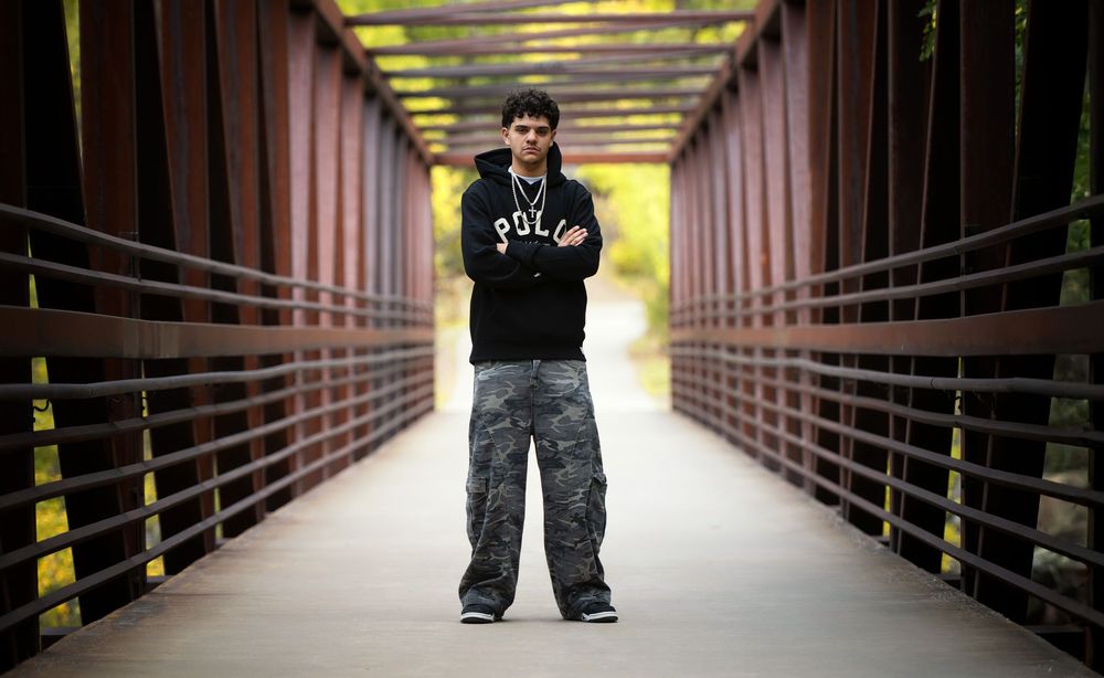 A Westminster Senior stands in the middle of a long covered walkway with yellow lighting and metal railings on both sides.