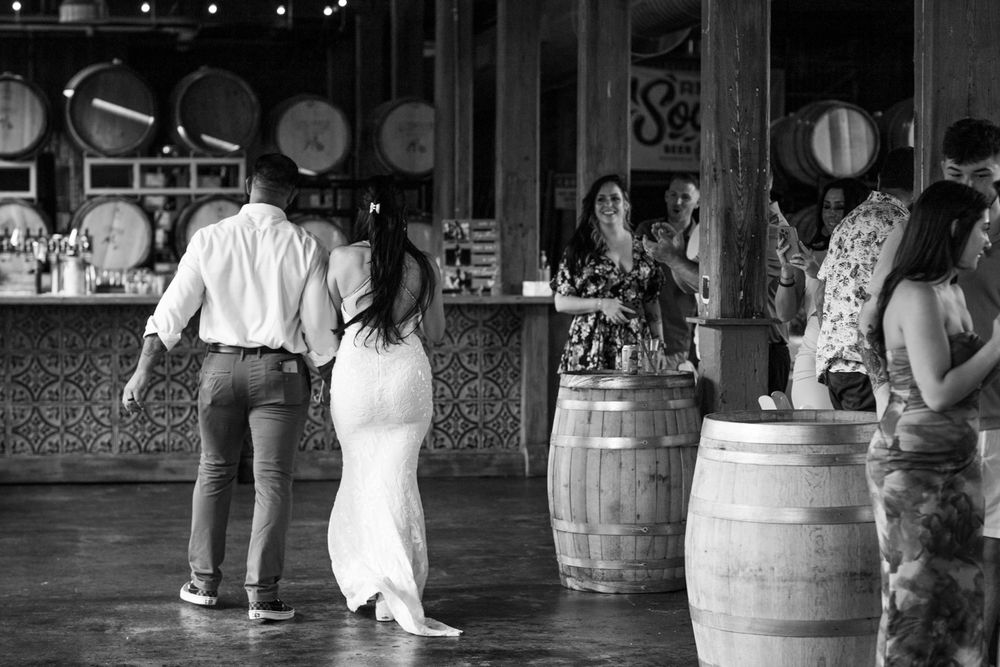 Couples dancing together at a rustic wedding reception venue with wine barrels and ambient lighting.
