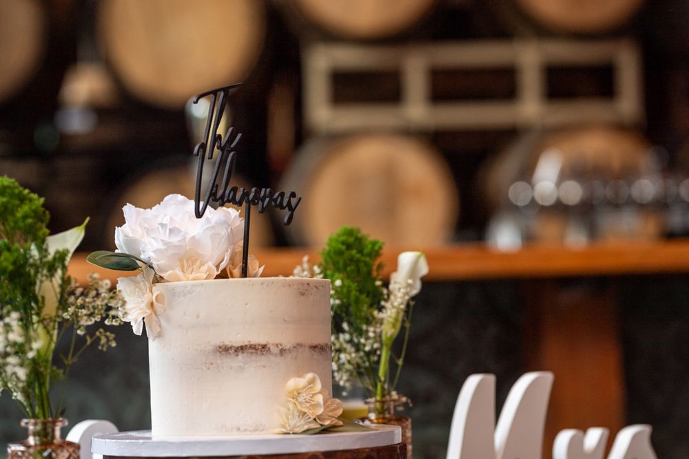 Elegant rustic wedding reception with wine barrels and floral decorations in a cozy indoor venue.