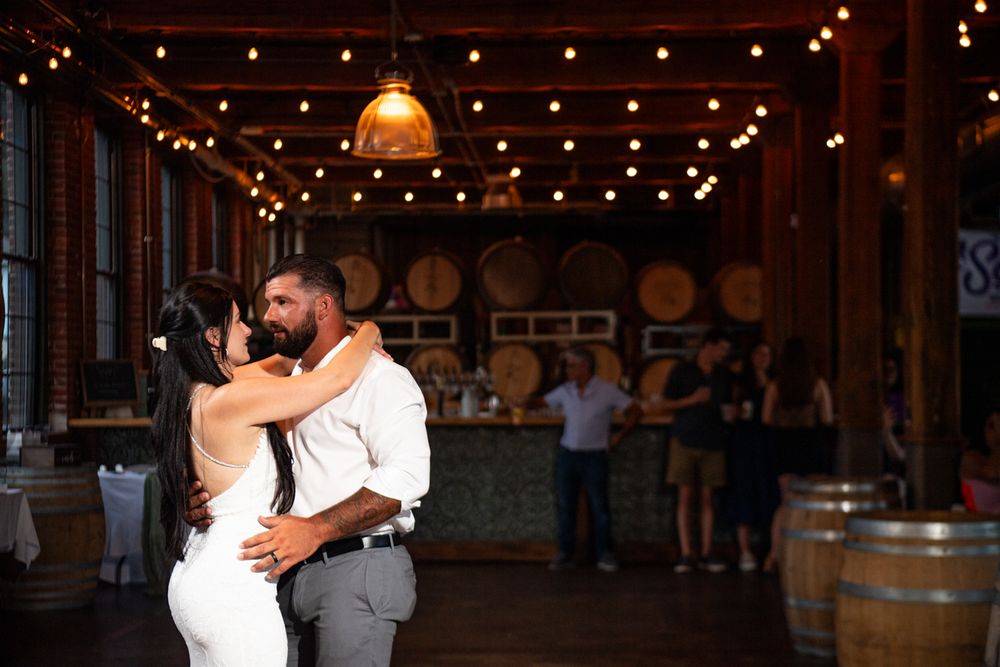 A couple shares a romantic dance at their wedding reception under warm string lights and elegant decor.