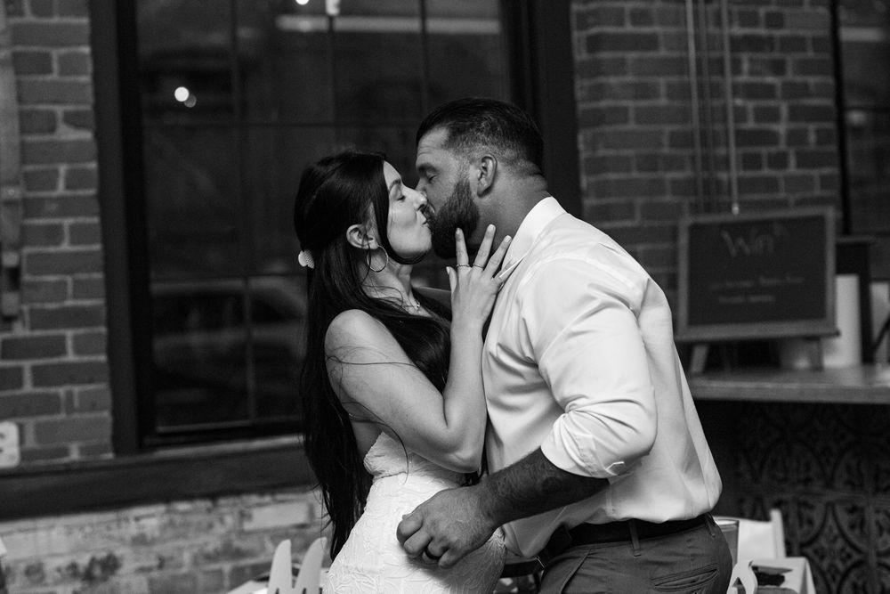 A romantic black and white photo series showing a couple sharing intimate moments against a brick wall.