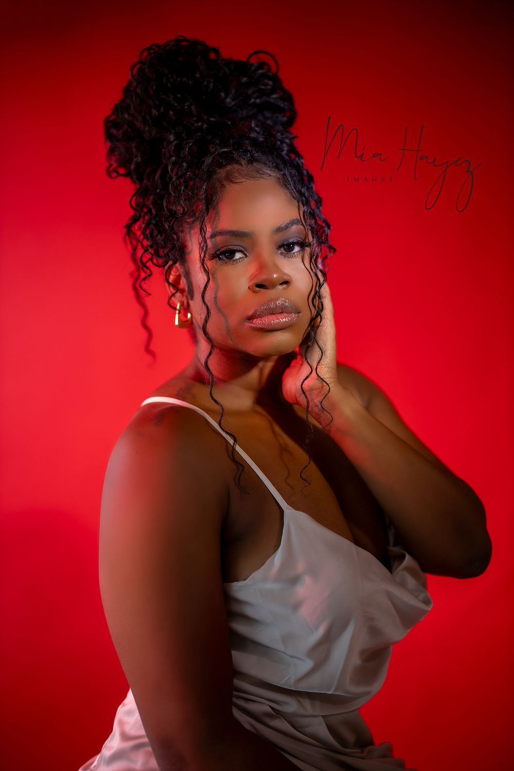 Dramatic portrait series against a red background with artistic lighting and white satin top.
