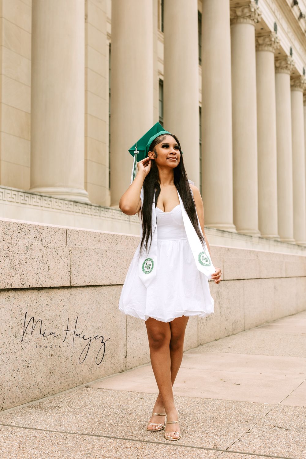 Graduation photos in white dress against classical column architecture with green bow.