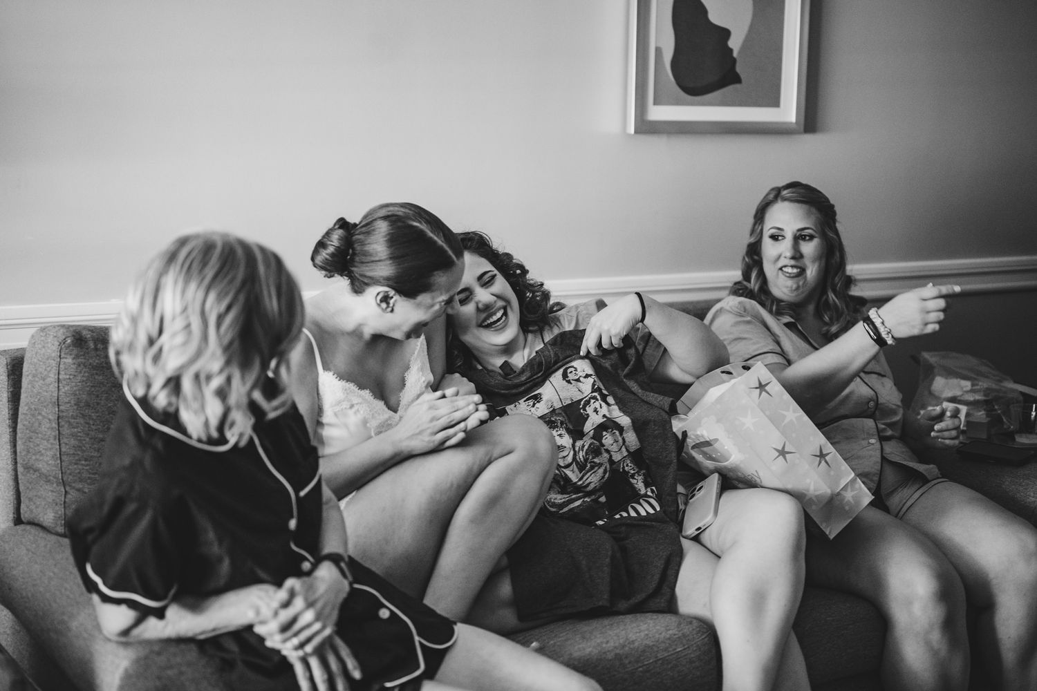 A candid moment of laughter and joy shared on a couch during wedding preparations.