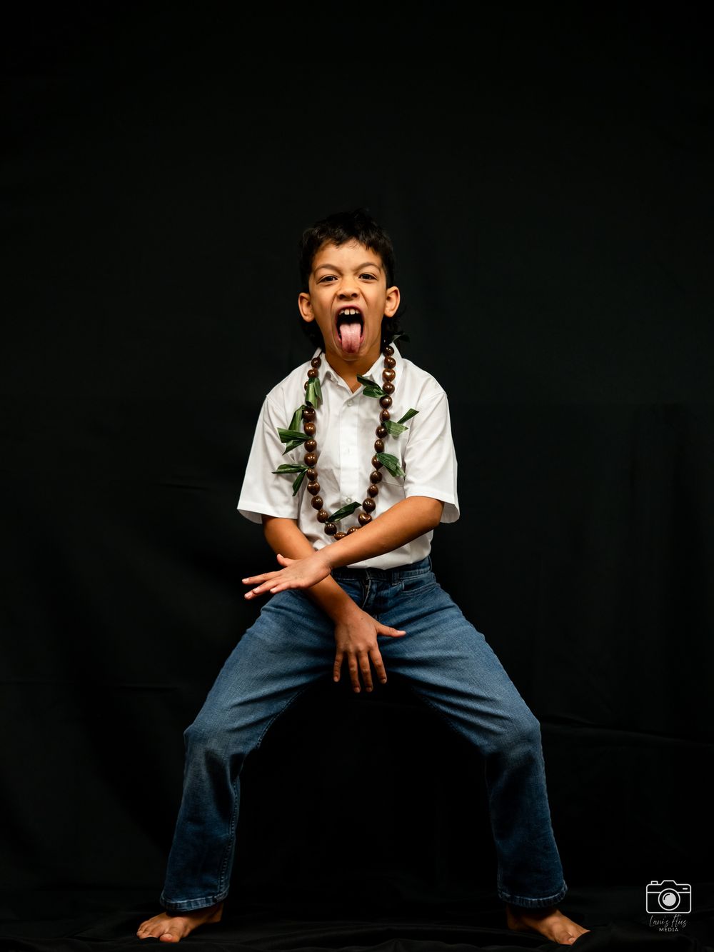 Young performer in white shirt and blue jeans strikes dynamic poses against dark background during photo shoot.