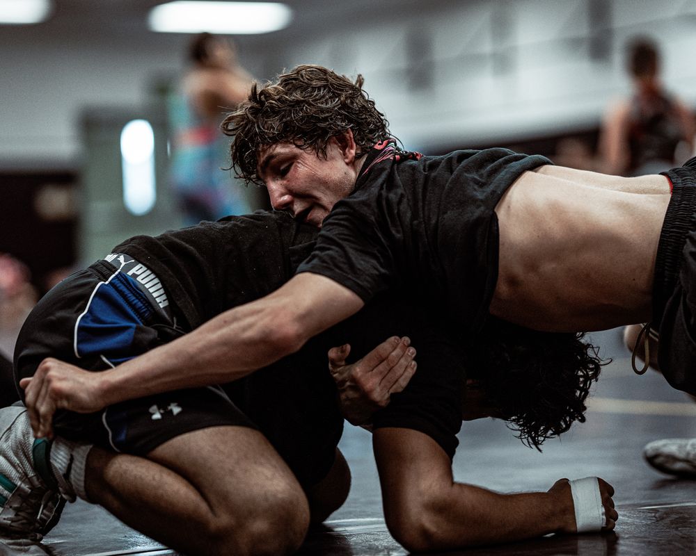 Wrestlers engage in ground techniques during a competitive match on the mat.