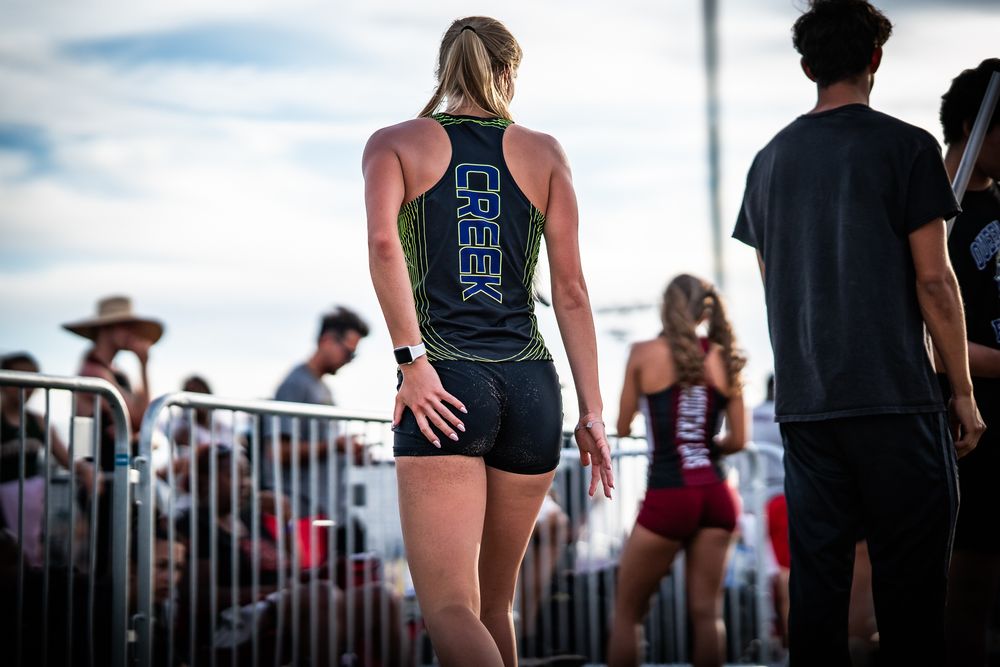 Athletes line up along a fence during an outdoor sporting competition.