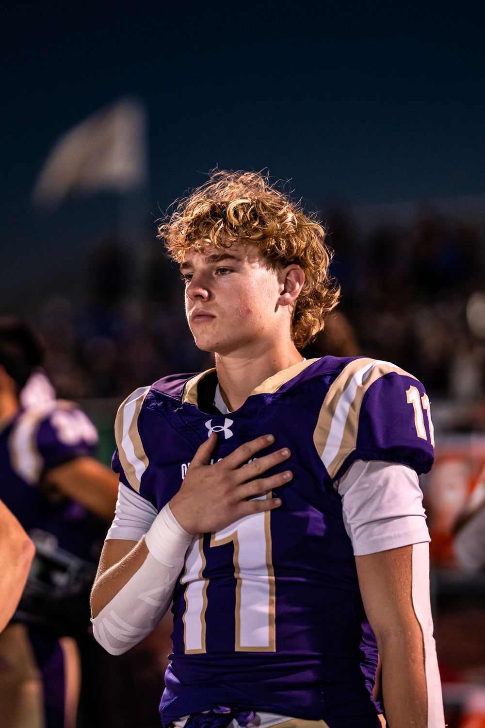 Football players in purple uniforms standing during what appears to be a pre-game ceremony.