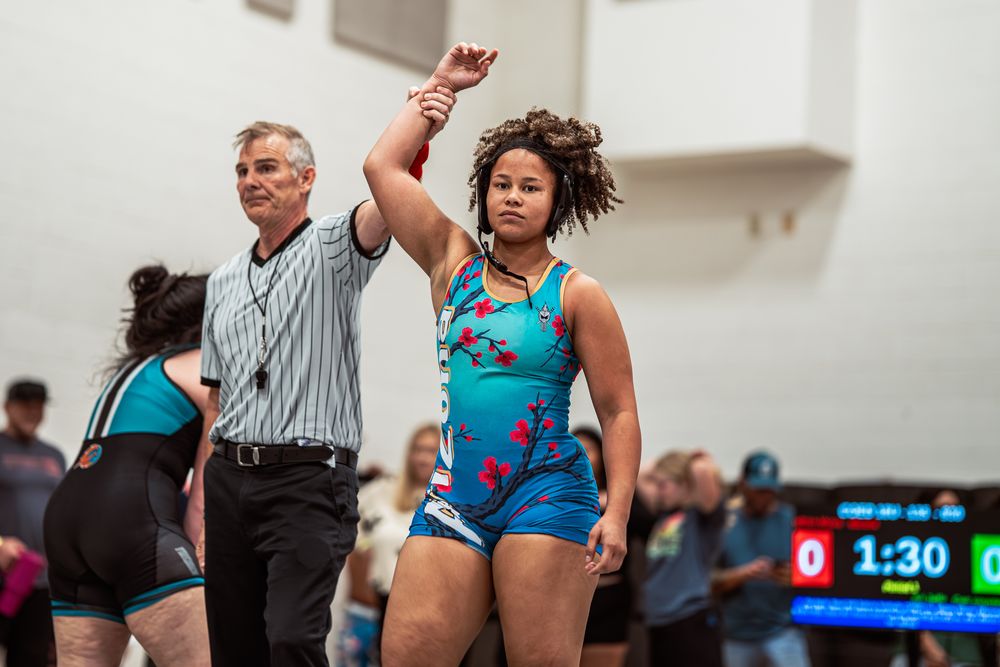 Athletes competing in a gymnastics competition with judges watching.