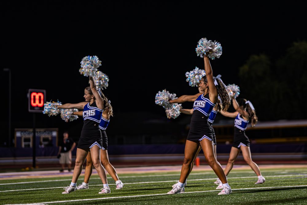 Cheerleaders execute synchronized formations during a nighttime field performance.