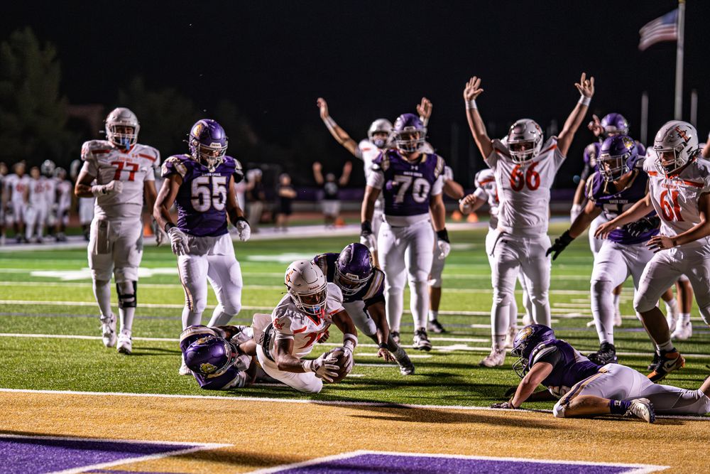 Football players dive for the ball during an intense play on the field.