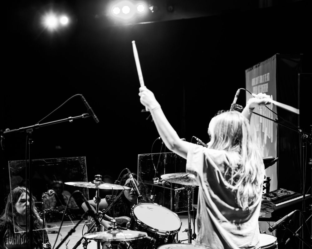 A dynamic black and white photo montage shows musicians performing energetically on stage during a rock concert.
