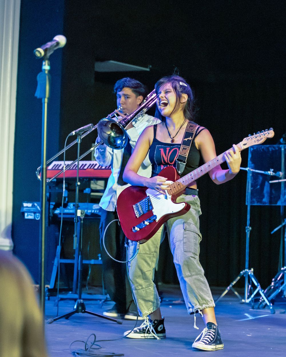 Musicians perform energetically on stage with guitars and microphones during a live concert performance.