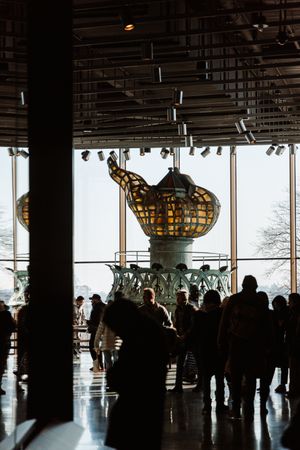 Silhouettes of visitors in observation deck viewing Manhattan skyline through windows.
