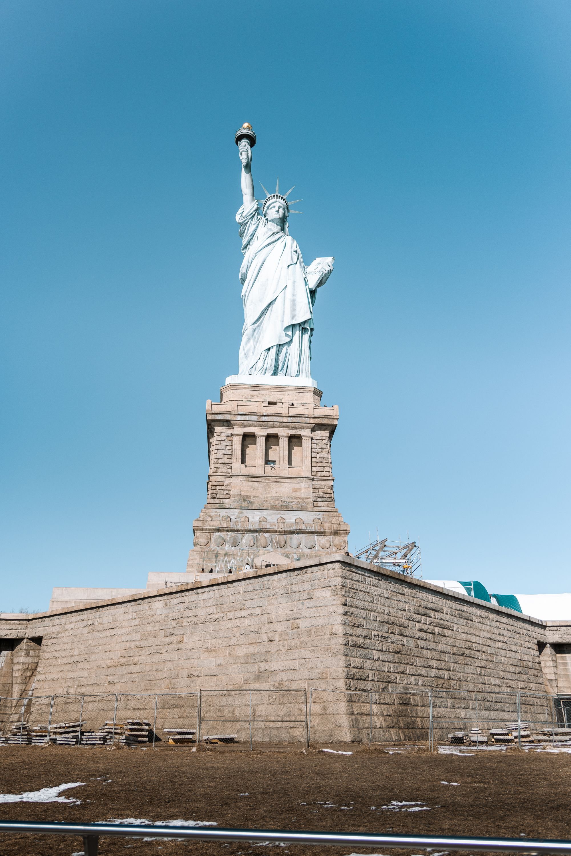 Statue of Liberty photographed from ground level against bright blue sky.