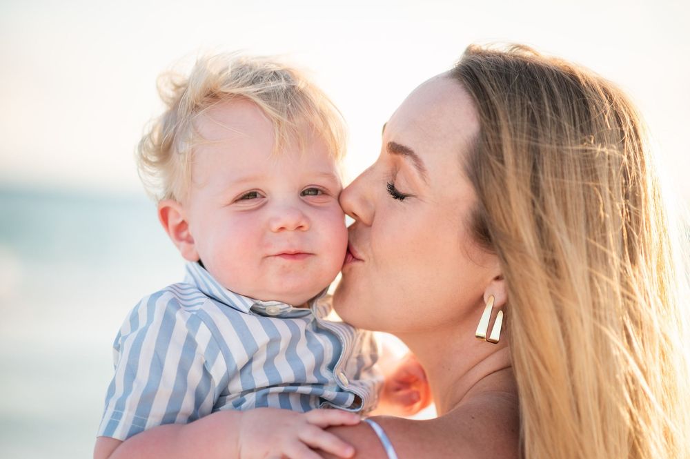 A tender beach portrait showing affection and connection during golden hour on white sand.