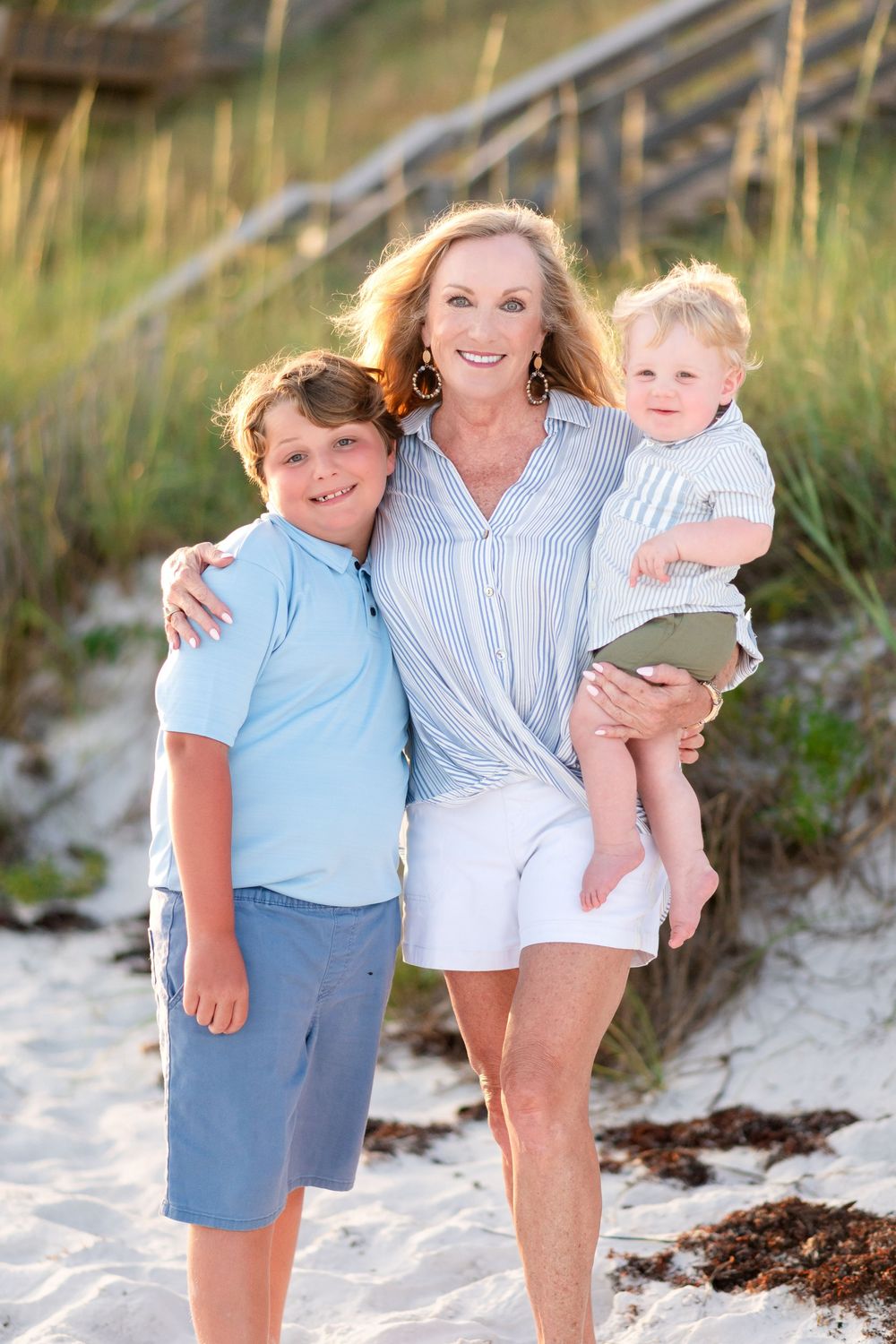 A beach photoshoot with people wearing coordinated blue and white outfits on the sand in Seagrove Beach, Florida